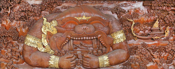 Wall Mural - Traditional Thai carve art about Ramayana story at the temple wall Wat Pho in Bangkok, Thailand.