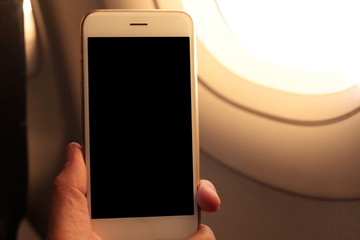 Poster - Hand holding mockup smartphone with plane window background