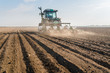 Farmer with tractor seeding - sowing soy crops at agricultural field in spring