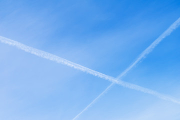 Two intersecting Condensation tracks of airplanes on clear blue sky. With place for your text, for background use.