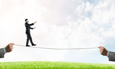 Business concept of risk support and assistance with man balancing on rope