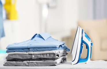 Wall Mural - Electric iron and pile of clothes on blurred background