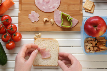 Woman making tasty sandwich on table