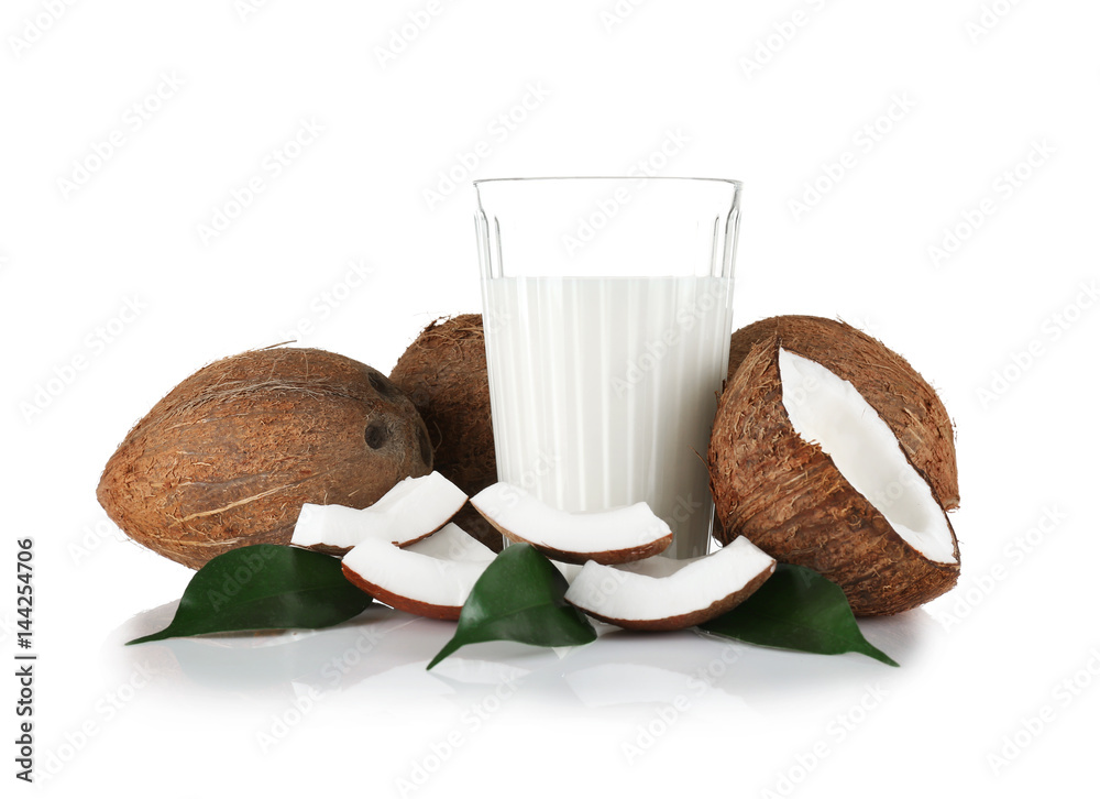 Glass of coconut milk with nuts on white background