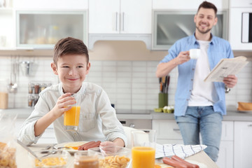 Poster - Boy having lunch at home and his father with cup of tea and newspaper on background