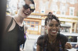 © HEX - Two young women looking through a window and smiling.
