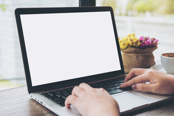 Mockup image of hands using laptop with blank white screen on vintage wooden table in cafe