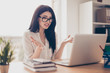 Close-up portrait of beautiful young businesswoman at a loss with glasses at office sitting at the table, work with laptop