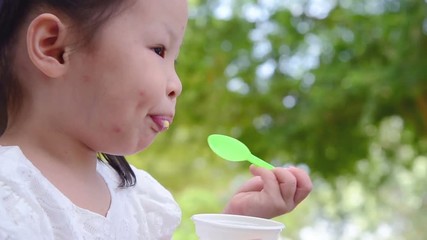 Wall Mural - Little asian girl eating ice cream in park
