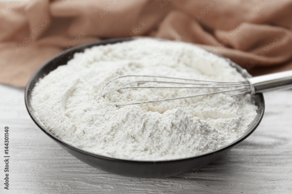 Bowl full of white wheat flour on wooden kitchen table