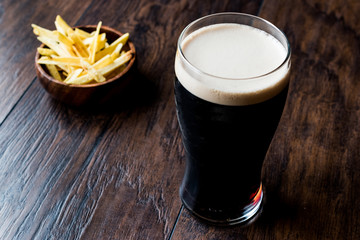 Poster - Dark Beer with snacks potato chips on wooden surface.