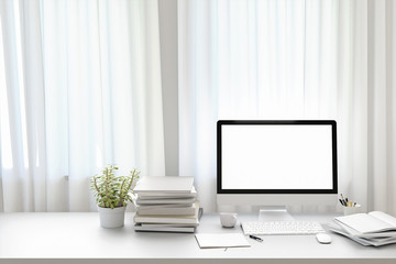 Poster - Front view of workpark with blank white computer screen, coffee cup, and book in home work. Mock up , 3D render