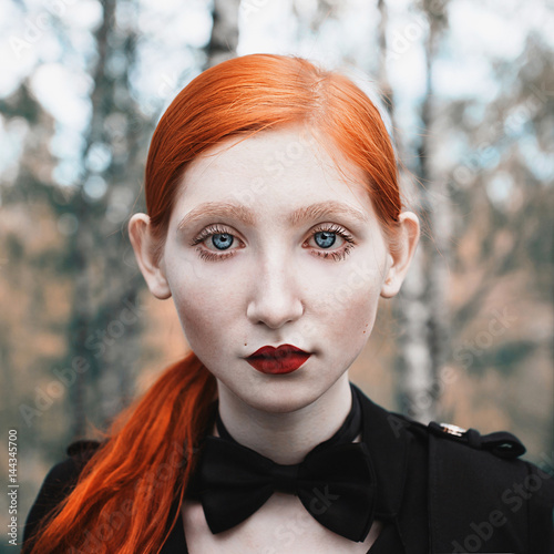 Portrait Of A Woman With Long Red Hair In A Black Jacket And A Bow Tie