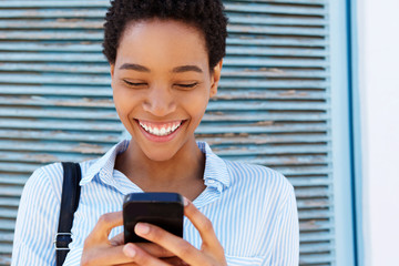 Close up smiling young african woman holding mobile phone