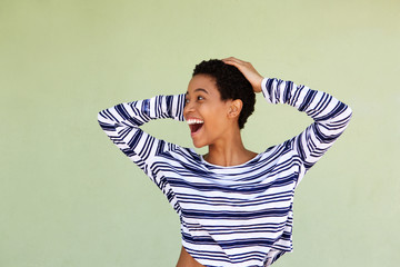 Wall Mural - young woman laughing with hand in hair against green background