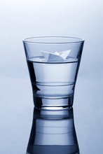 Glass Of Water With Paper Origami Boat Concept