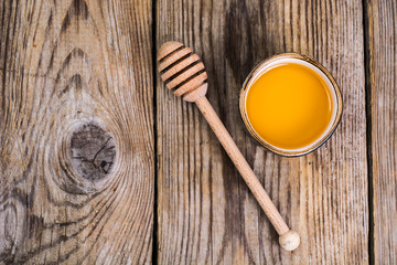 Canvas Print - Honey in bowl and spoon on wooden background