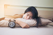 © Bavorndej - Beautiful asian woman sleep with vintage clock, Young woman Portrait in bedroom, vintage color tone.