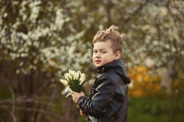 Wall Mural - the boy holds tulips on the background of a blooming garden .