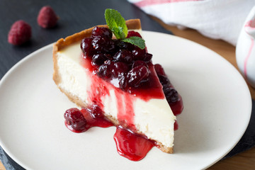 Wall Mural - Slice of cheesecake with cranberry sauce decorated with mint on white plate