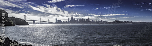 Plakat Panorama San Francisco i Bay Bridge. Widok miejski pokazuje budynki dzielnic biznesowych i drapacze chmur oraz Ocean Spokojny. Obraz przedstawia turystykę w Ameryce.