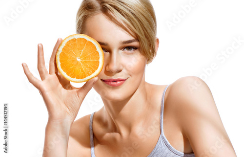 Fotografía Lovely girl holding a slice of orange in front of her face and smiling