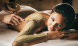 © gudenkoa - The girl enjoys mud body mask in a spa salon. Focus on the hand with the stick. Luxury treatment.