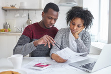 Young African American Wife And Husband Sitting At Home With Laptop, Calculator And Papers Doing Paperwork Together, Analyzing Expenses, Planning Family Budget And Calculating Bills, Having No Money