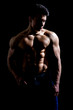 © theartofphoto - Handsome young muscular man shirtless wearing jeans, on dark background in studio shot