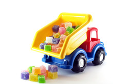 Close Up Toy Dump Truck Pouring Colorful Cube Jelly Candies On White Background, Sweets And Toy For Kid Party Decoration