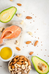 Wall Mural - Healthy food. Products with healthy fats. Omega 3, omega 6. Ingredients and products: trout (salmon), flaxseed oil, avocado, almonds, cashews, pistachios. On a white stone table. Copy space top view