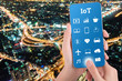 © kwanchaift - woman hand using smart phone in concept internet of things with night modern city background