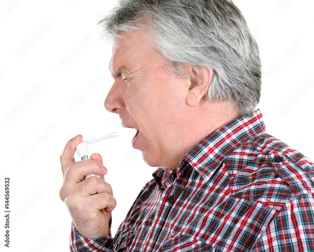 Sick senior man using throat spray on white background