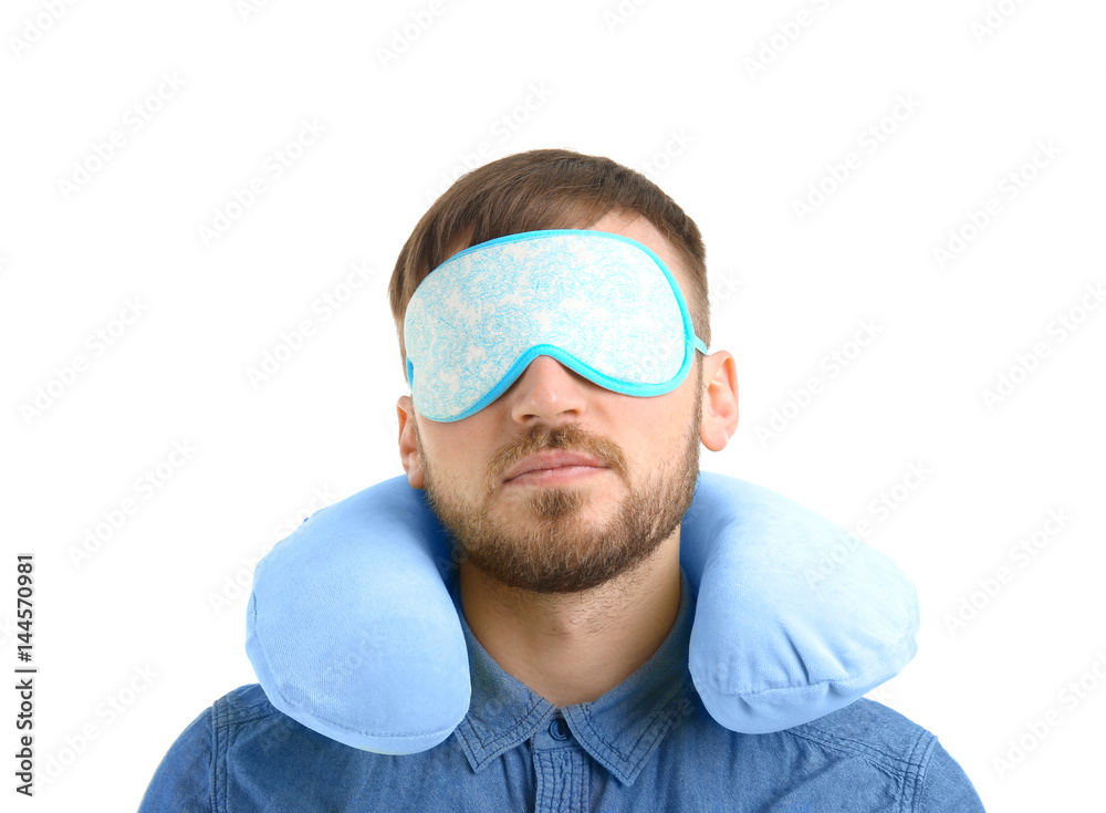 Young man with travel pillow and sleep mask on white background