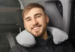 Young man with travel pillow in car