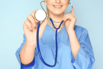 Poster - Young medical assistant with stethoscope on color background, closeup