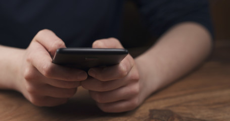 Wall Mural - young female teen hands using smatphone sitting at the table closeup, 4k photo