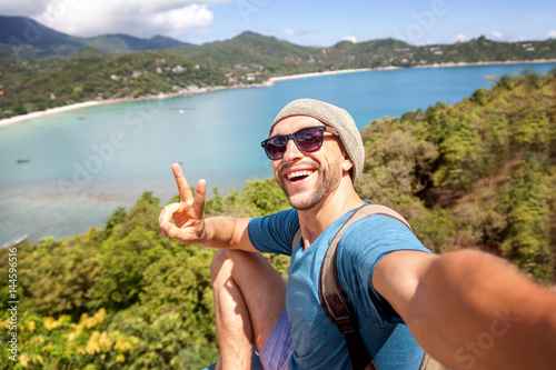 Fotomural Young male hipster traveler doing selfie overlooking the tropical sea