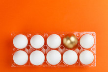 Transparent Packaging Of Chicken Eggs With One Golden Egg On An Orange Background.