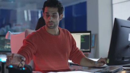 Young creative computer game designer working with colleagues in dark office