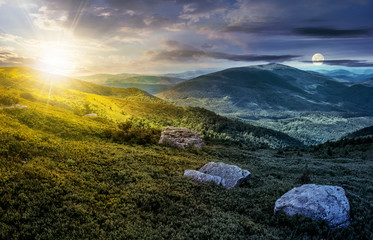 Wall Mural - day and night time change concept image. huge stones among the grass on top of the hillside meadow n