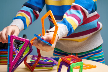 Small boy is crafting with colorful magnetic construction set. C
