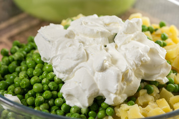 White sour cream on the cooked green peas in the bowl