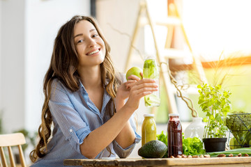 beautiful happy woman sitting with drinks and healthy green food at home. vegan meal and detox conce