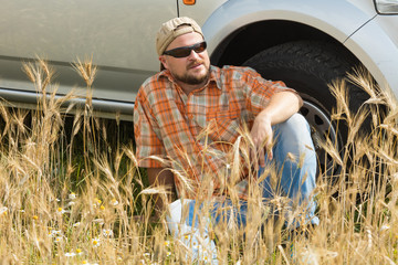 Wall Mural - Farmer in sunglasses sitting near car