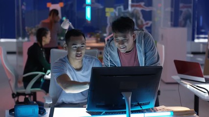  Young game designers looking at computer screen & discussing ideas