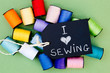 I love Sewing - with blackboard and colorful cotton thread reels on green cardboard background
