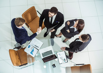 handshake of business partners after discussion of the contract next to a Desk