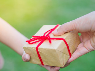 Wall Mural - holidays, present, christmas, childhood and happiness concept - close up of child and mother hands with gift box over green background