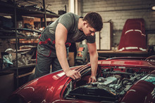 Mechanic Working On Classic Car Electrics In Restoration Workshop